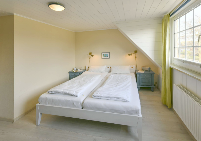 Helles Schlafzimmer mit Doppelbett, großem Kleiderschrank, warmen Farben und gemütlicher Atmosphäre in einer modernen Ferienwohnung.